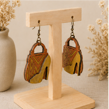 Cargar imagen en el visor de la galería, Angled view of Bag & Heels 3D wooden earrings on a light wood stand, showing the layered construction.