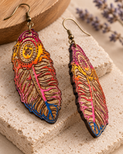 Cargar imagen en el visor de la galería, Angled side view of boho feather wooden earrings showing the 2 mm American linden wood thickness, dark laser-cut edges, detailed engraving, hand-painted finish and matching design on both sides.