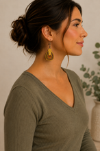 Cargar imagen en el visor de la galería, Model wearing Earth Echoes hand-painted wooden earrings with a soft olive top.