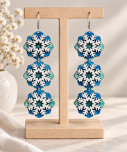 Cargar imagen en el visor de la galería, Frozen Sky layered snowflake wooden earrings in blue, icy green and white on a light wood stand