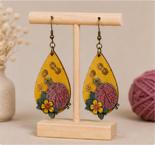 Cargar imagen en el visor de la galería, Hooked on Crochet wooden earrings displayed front-facing on a light wood stand.