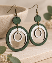 Cargar imagen en el visor de la galería, Lunar Dance wooden earrings shown at an angle to highlight the articulated green and white moving circle design