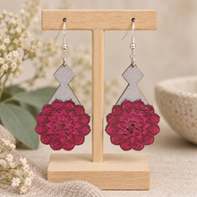 Cargar imagen en el visor de la galería, Mystic Mandala Bloom layered wooden earrings displayed front-facing on a light wood stand, showing the hand-painted magenta mandalas, gray geometric bases and silver-tone hooks.