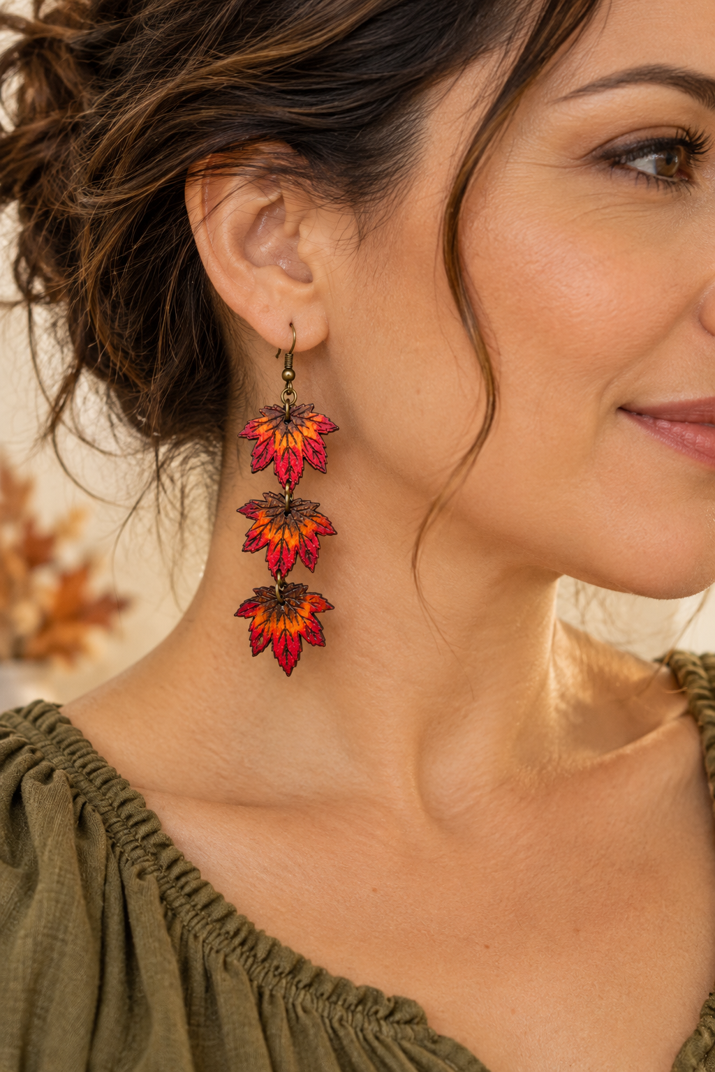 Modelo usando los aretes livianos Autumn Cascade con un top verde oliva, mostrando el diseño de tres hojas colgantes y sus colores otoñales.