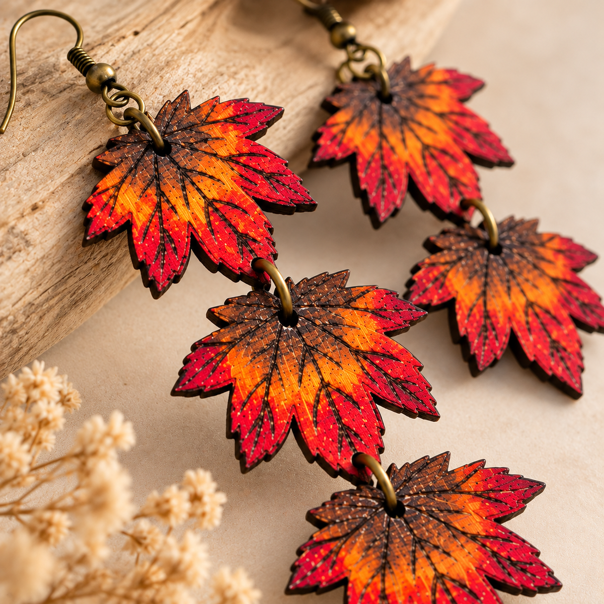 Primer plano de los aretes Autumn Cascade pintados a mano, mostrando las venas grabadas de las hojas de arce, la veta de la madera, los colores otoñales y los aros en tono bronce.