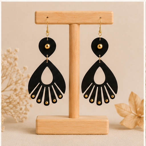 Ebony Moon wooden earrings shown from the reverse side on a light wood stand, showing the same black-and-gold design on both sides.