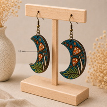Cargar imagen en el visor de la galería, Enchanted Forest Moon wooden earrings shown from the side on a light wood stand to highlight the 2.5 mm wood thickness.
