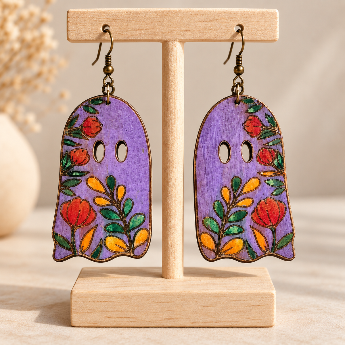 Floral Ghost hand-painted lightweight wooden earrings displayed on a light wood stand, showing the lavender floral design and bronze-tone hooks.
