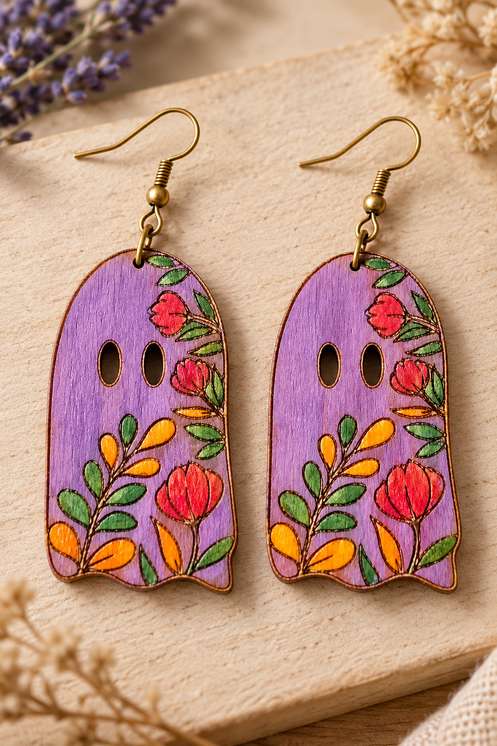 Close-up of Floral Ghost hand-painted wooden earrings showing the lavender paint, floral details, natural wood grain, scalloped edges, and bronze-tone hooks.