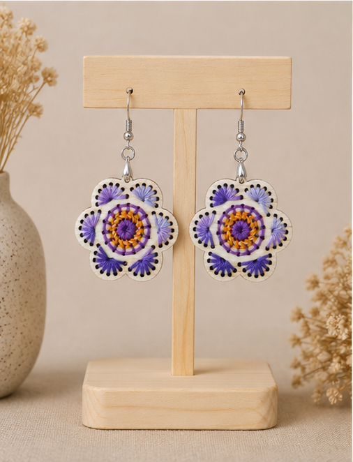 Lavender Bloom hand-embroidered wooden earrings displayed front-facing on a light wood stand.