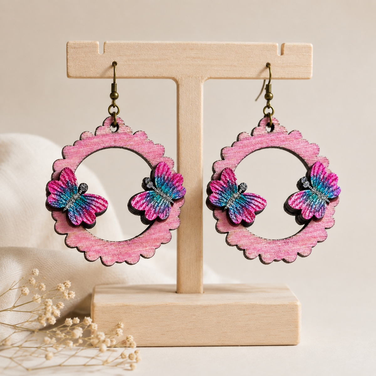 Mariposa Serena layered butterfly wooden earrings on a light wood stand