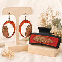 Cargar imagen en el visor de la galería, Tribal Feather large hair clip and matching lightweight wooden earrings displayed together on a light wood stand and plinth.
